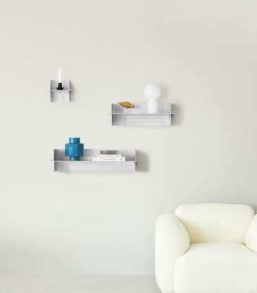 Läpinäkyvät Normann Copenhagen -seinähyllyt koristeellisilla asusteilla minimalistisessa olohuoneessa.