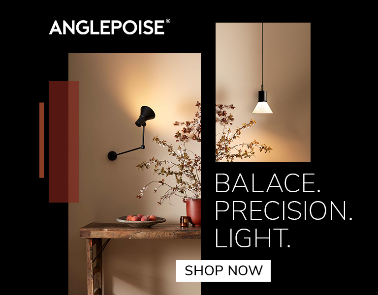 shop now A black Anglepoise wall lamp illuminating a rustic wooden table with a bowl of fruit and a vase of branches. Another minimalist pendant light hangs on a beige wall. Text reads: ‘Anglepoise. Balance. Precision. Light.’ A button says ‘Shop Now.’